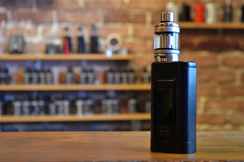 A mod vape with a black coloured atomiser standing upright on the table.