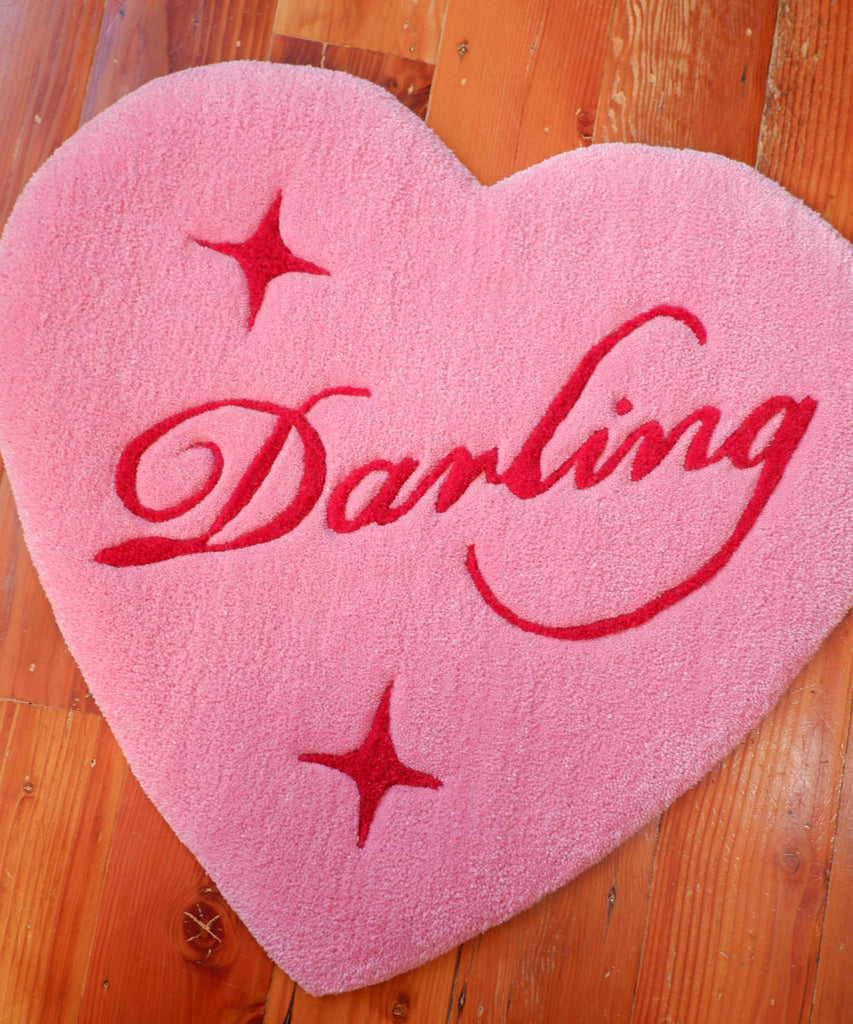 a pink heart-shaped hand-tufted rug with the word "Darling" on the inside and star details surrounding it