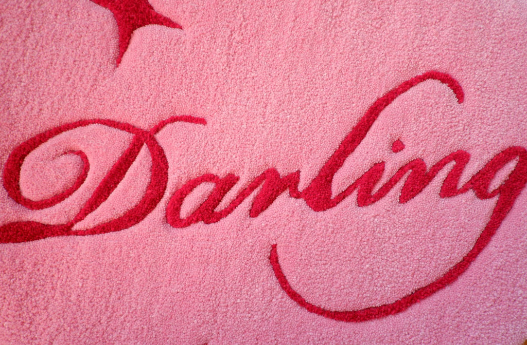 a pink heart-shaped hand-tufted rug with the word "Darling" on the inside and star details surrounding it