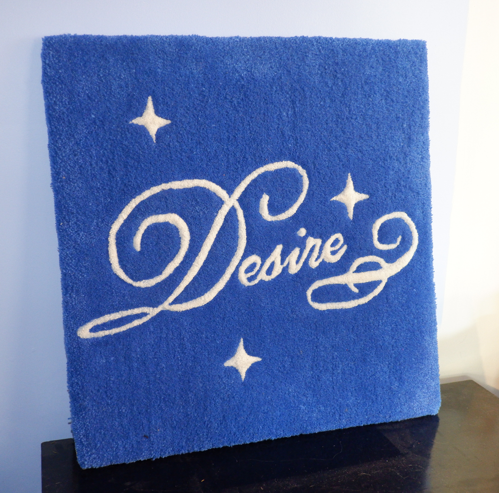 hand-tufted rug wall hanging in royal blue with the word "Desire" in script text