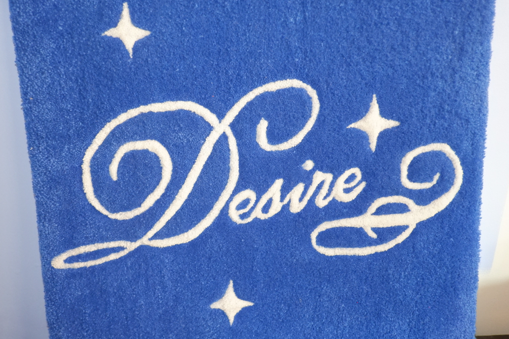 hand-tufted rug wall hanging in royal blue with the word "Desire" in script text