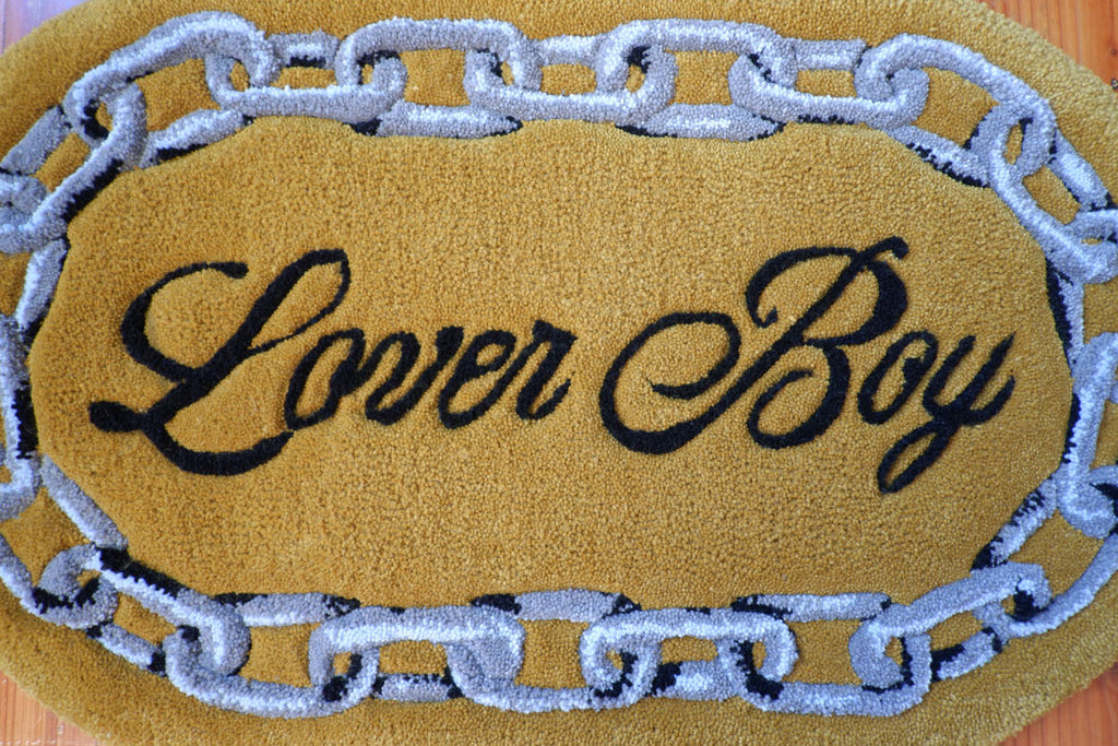 hand-tufted queer rug that says Lover Boy with a chain around it.