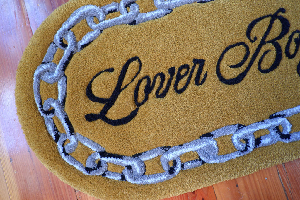 hand-tufted queer rug that says Lover Boy with a chain around it