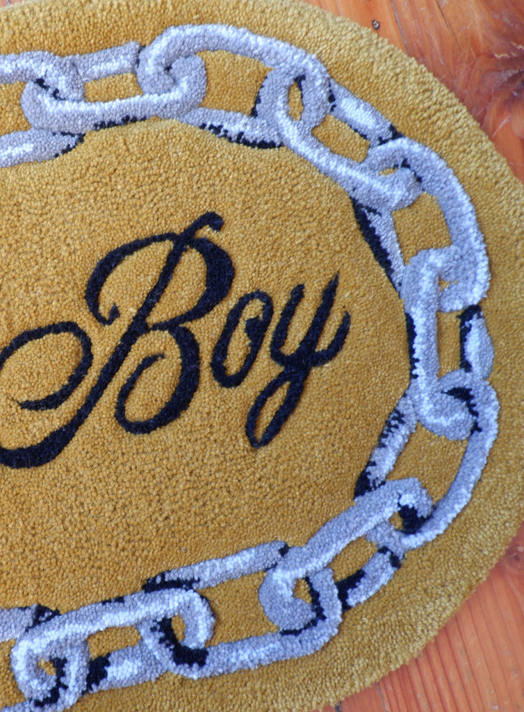 hand-tufted queer rug that says Lover Boy with a chain around it.