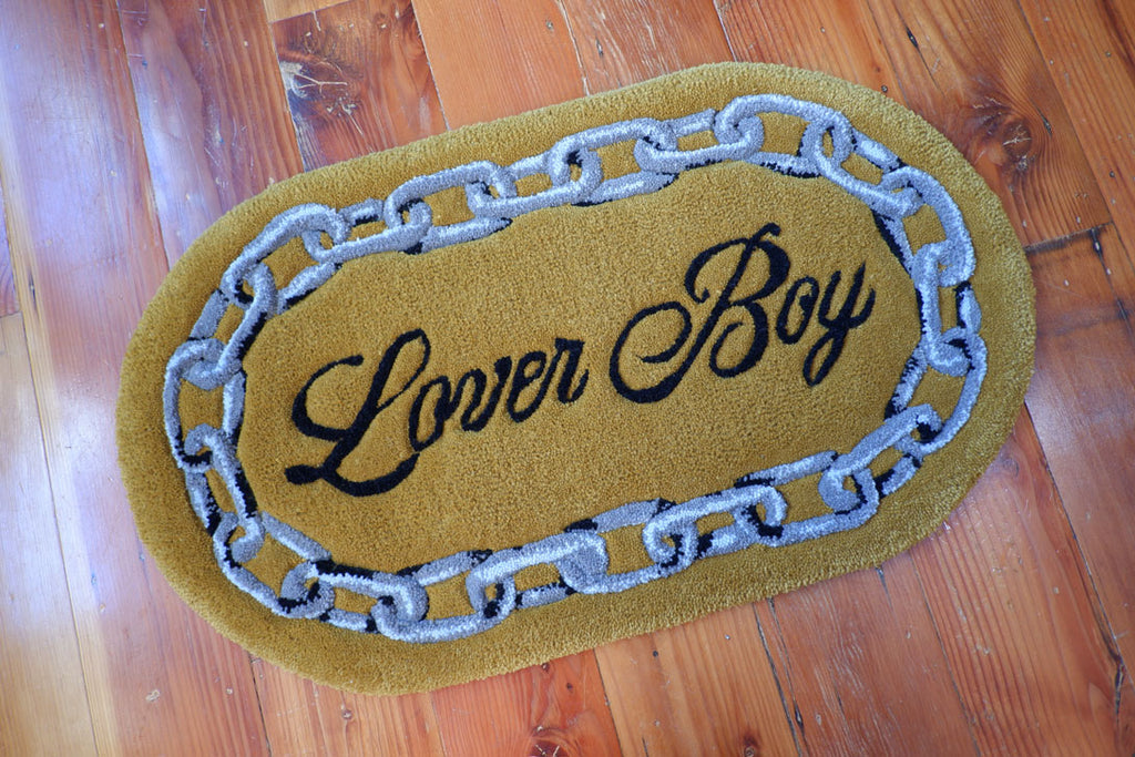 hand-tufted queer rug that says Lover Boy with a chain around it.
