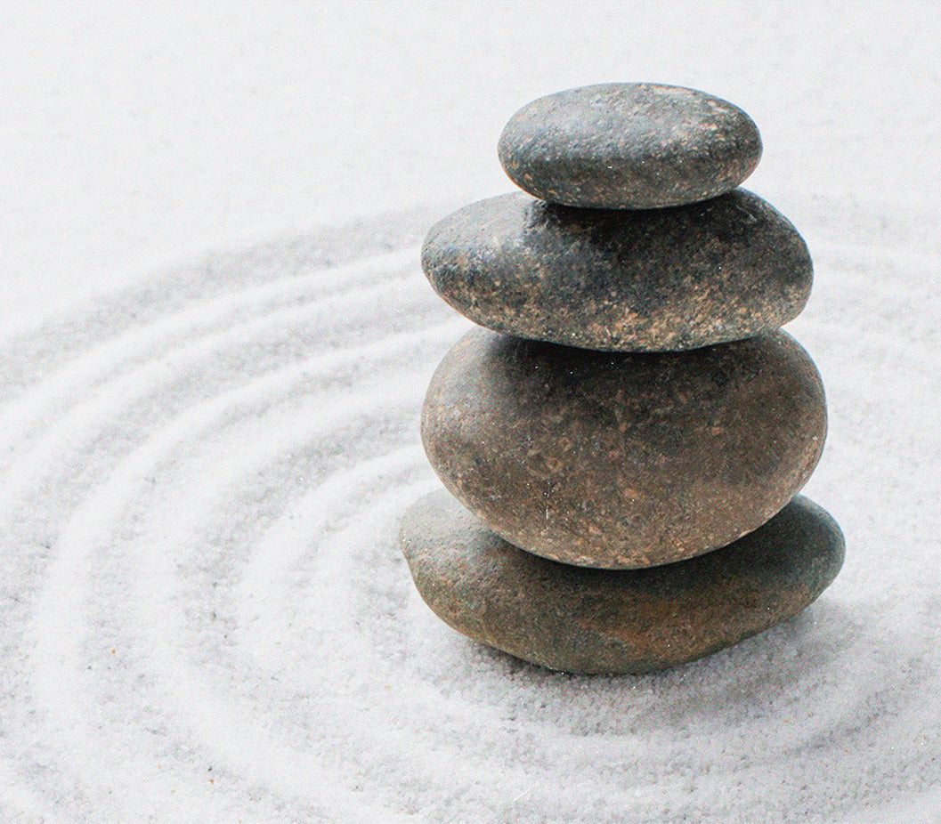 Astrologer and tarot reader Chris Corsini blog post, a fog clearing visualization exercise for any time you feel unclear, four round stones balancing on top of eachother, sitting in white sand.