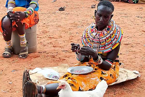 A Samburu woman makes ornaments using beads.