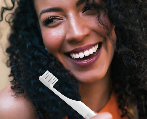 A person holds a XF21 toothbrush while smiling brightly.