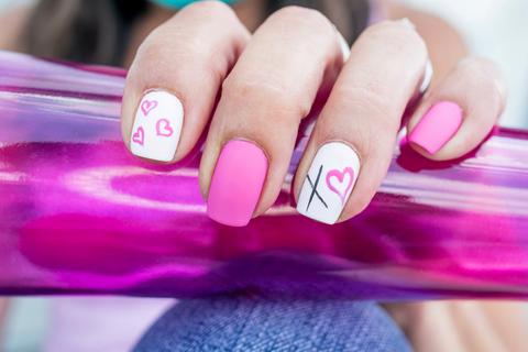 Light candy pink nails and white nails. The white nails have little pink outlines of hearts and black x shapes for kisses.