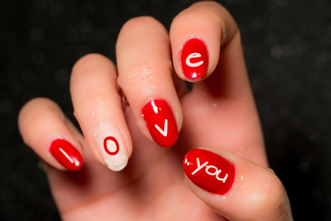 Red nails with ‘Love you’ painted on them in white.