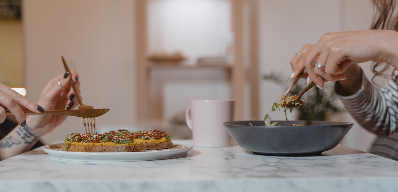 Zwei Menschen sitzend beim Essen gegenüber