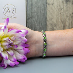 Close-up of a 4in1 Magnetic Bracelet adorned with Swarovski Peridot crystals on a woman’s wrist.