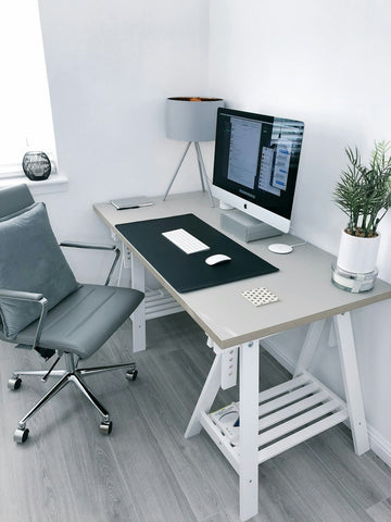 A modern and neat home office setup with a clear focus on ergonomic design. The desk is positioned at a comfortable height with a large computer monitor set at eye level to prevent neck strain. The office chair is adjustable with lumbar support to promote a good seated posture. Surrounding the workspace are tidy, calming elements like a potted plant, adding to the atmosphere conducive to both productivity and wellness.