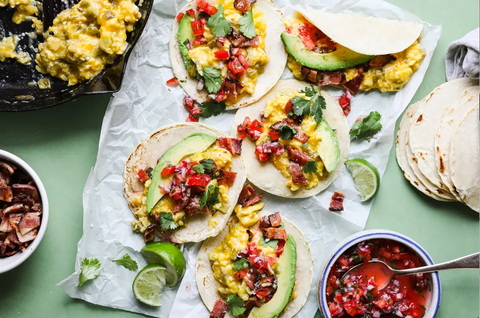 These Breakfast Recipes Will Set You Up for a Healthy Day: Several breakfast tacos sit on a sheet of parchment paper surrounded by bowls of toppings.