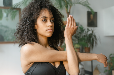  Should You Stretch After Working Out? Yes, and Here's Why: A woman stretches her arm across her chest.