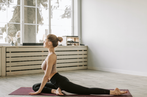 <p><span style="font-weight: 400;">Should You Stretch After Working Out? Yes, and Here's Why: A woman on a yoga mat performs a pigeon pose stretch.