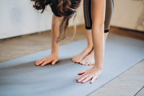 Should You Stretch After Working Out? Yes, and Here's Why: A woman on a yoga mat performs a forward bend.