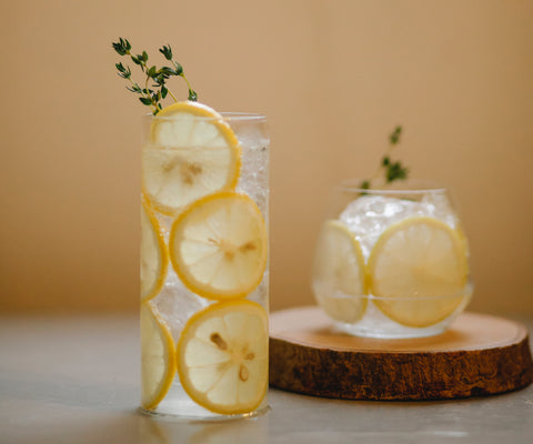 <i><span style="font-weight: 400;"> </span></i><span style="font-weight: 400;">3 Water Infusions to Help You Hydrate: A glass with lemons lining the inside sits on a concrete countertop.