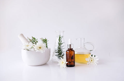 Ayurvedic herbs with body oil and flower on white table