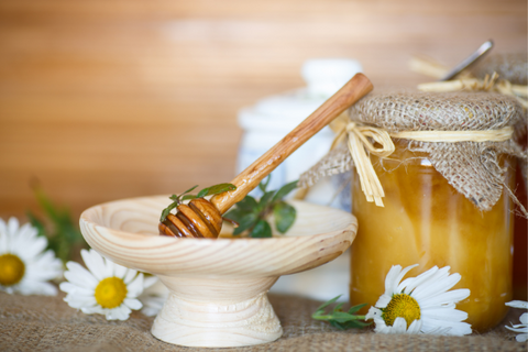 Fresh honey in glass jar along with dipper on a wooden table