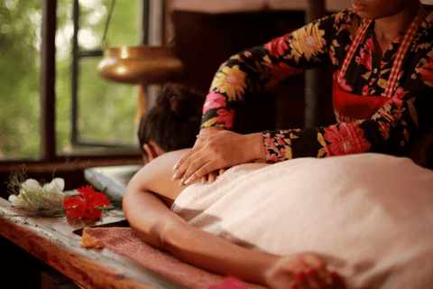 An asian female masseur applying pressure on body of a female, with both hands on her back