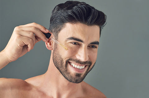 men is applying anti aging serum on his face