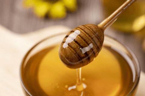 A glass bowl filled with honey and honey spoon dipped in it