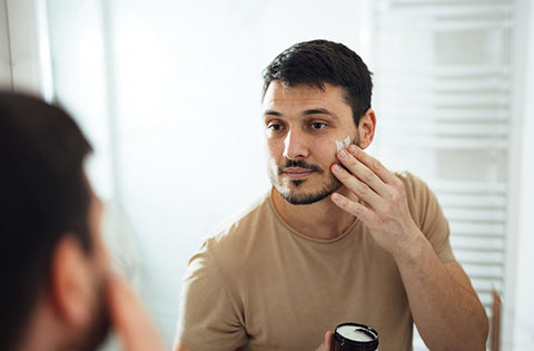 men is applying anti aging men's cream on his face