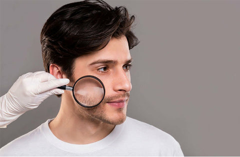 somebody is testing men skin by placing magnifying glass