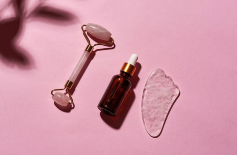 serum for face, jade roller and gua sha are on table