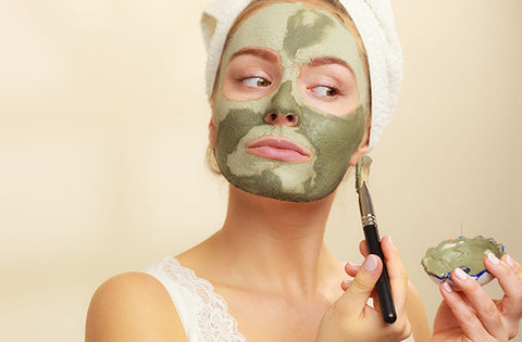 Lady is applying face mask on her face by brush