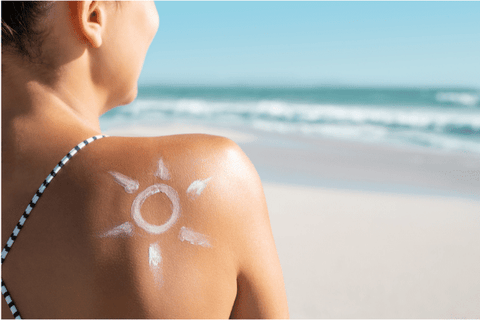 sun drawn with a sunscreen on the back of a lady standing on a beach