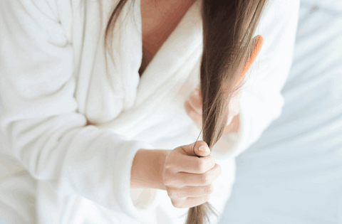 girl is applying hair oil on her hair ends