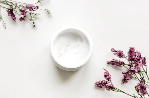 face cream with purple flowers in placed on white table 