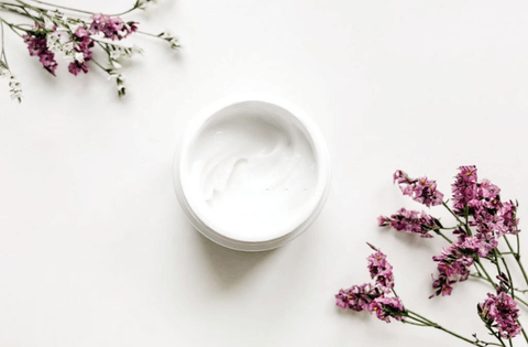 face cream with purple flowers in placed on white table