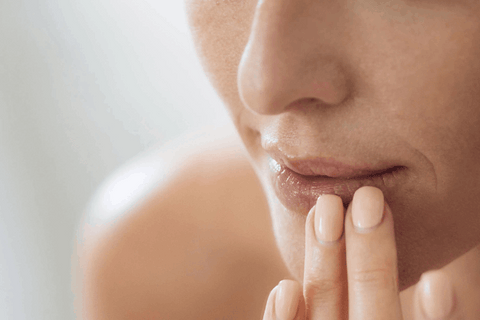 Girl is touching her chapped lips with her fingers
