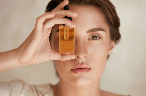 Girl is holding kumkumadi tailam bottle in front of her eyes 