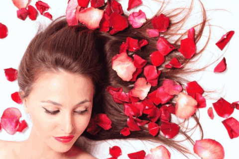 lady is lying with her open hairs that is surrounded by rose petals