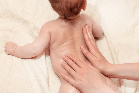 mother is giving back massage to baby with nalpamaradi oil 