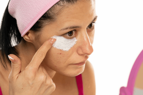 Girl is applying dark circle remover cream under her eyes