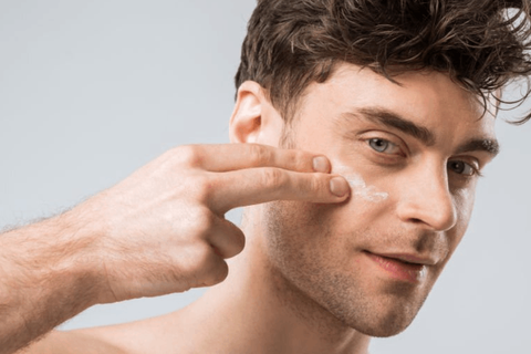 man is applying face cream on his cheeks by his 2 fingers