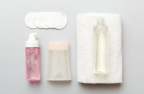 face wash, towel, cotton wipes are on grey table