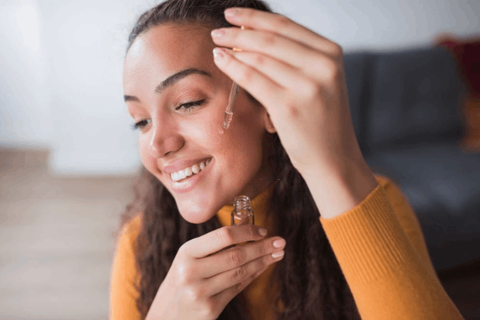 Girl is applying kumkumadi tailam on her cheek