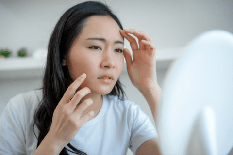 A worried women analyzing her face in the mirror