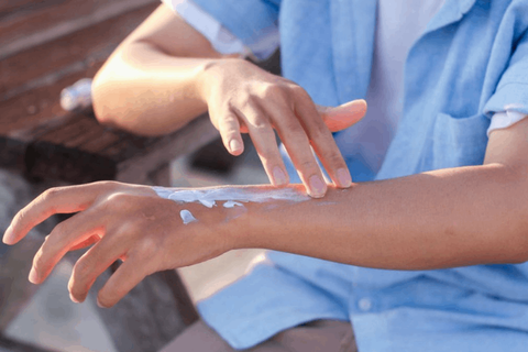 girl is applying sunscreen on her tan hands 