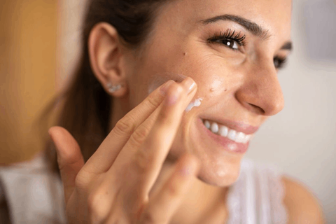 girl is applying anti aging cream on her face 