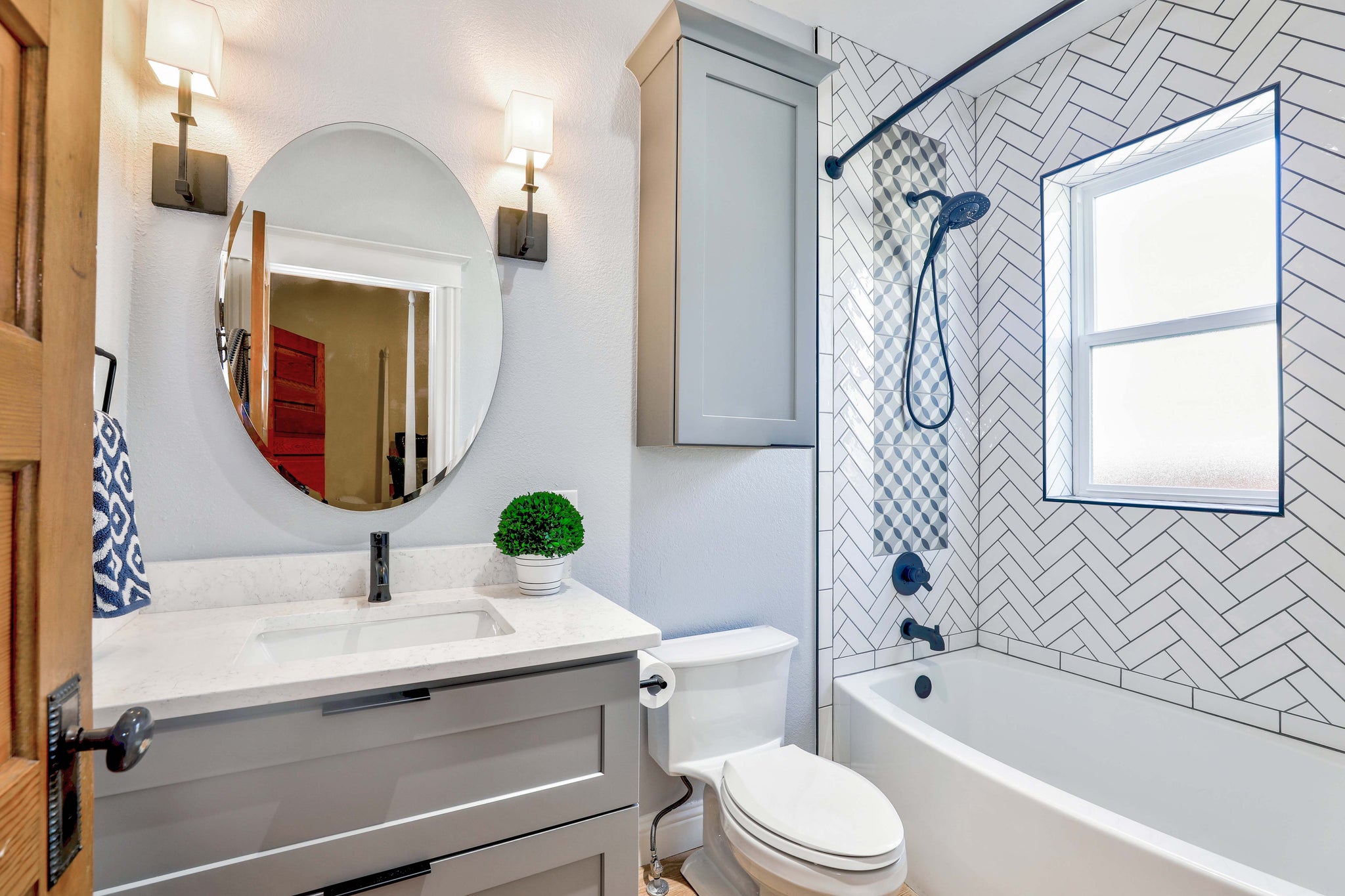 Transitional bathroom with shaker style vanity, round mirrors, and white backsplash tub