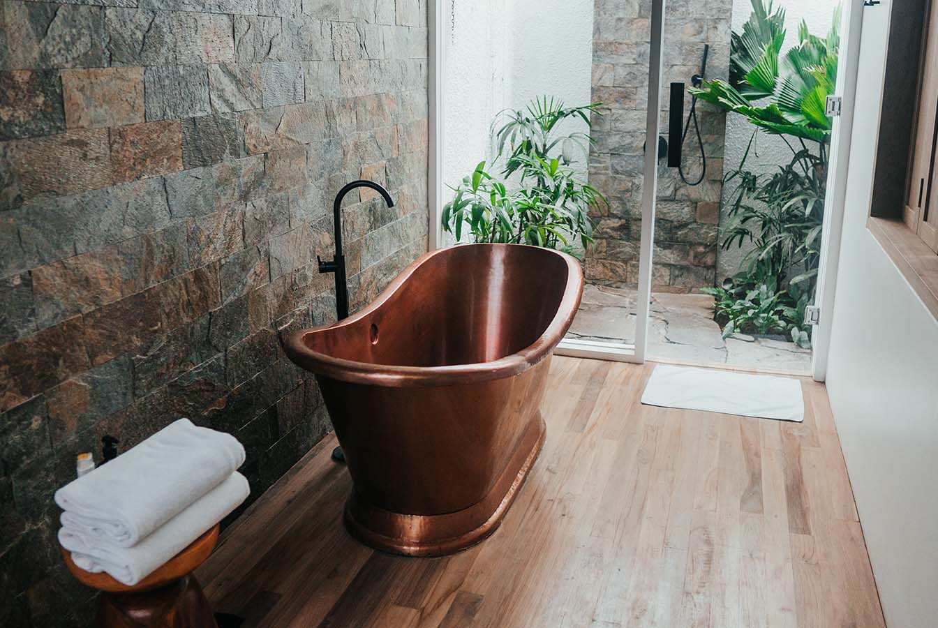 copper bathtub is modern bathroom with tropical plants