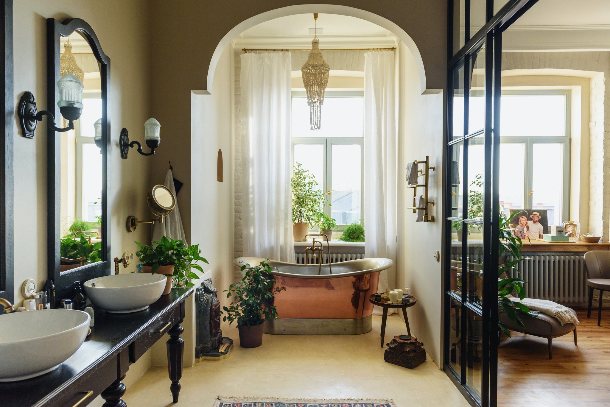 transitional bathroom with wooden carved vanity table with vessel sink, copper bathtub and chandelier overhead