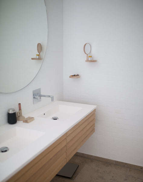 wall mounted chrome faucet on top of a light oak floating vanity